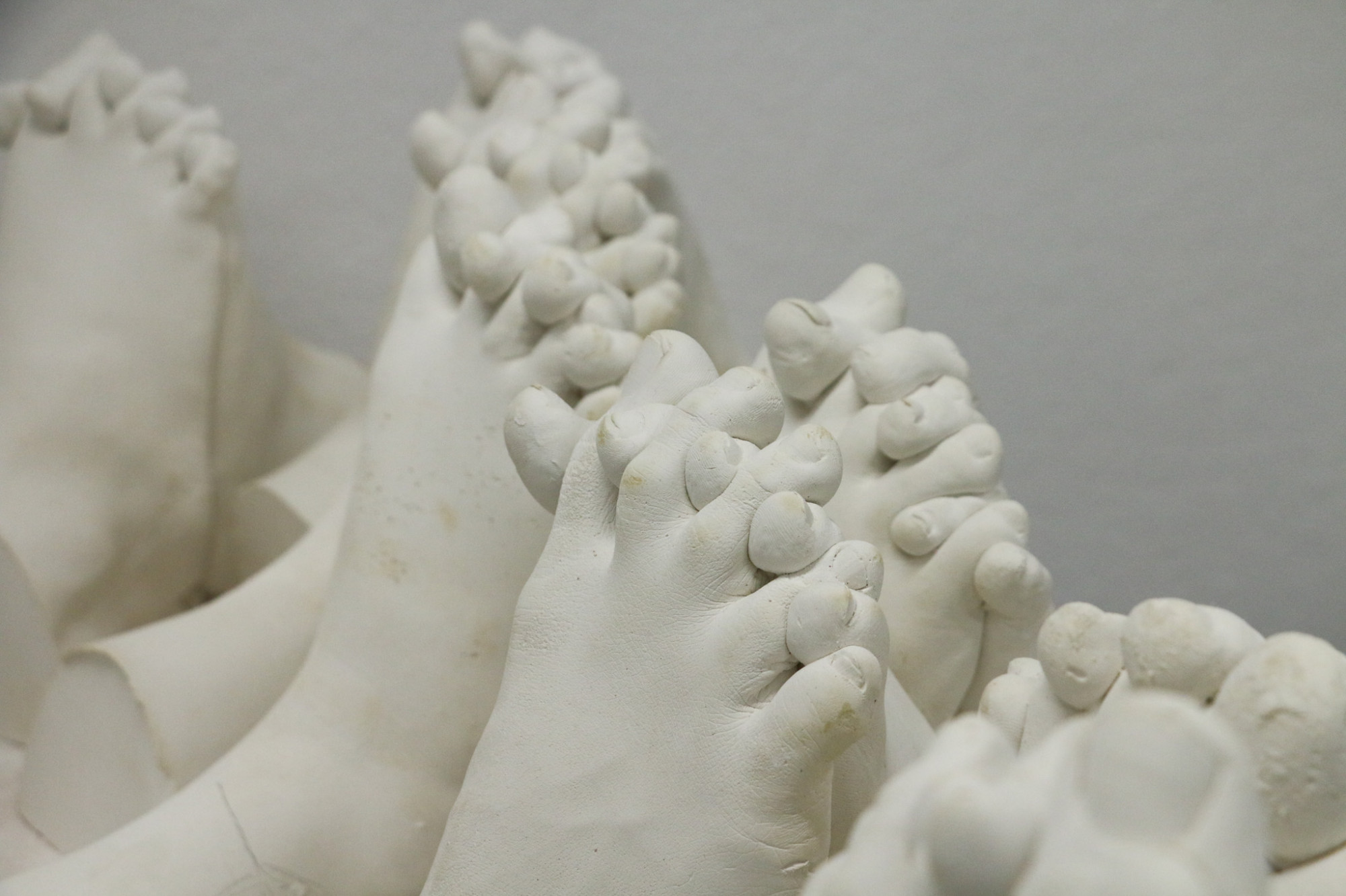 A series of cast white scultpures that look like pairs of feet interlocking toes.