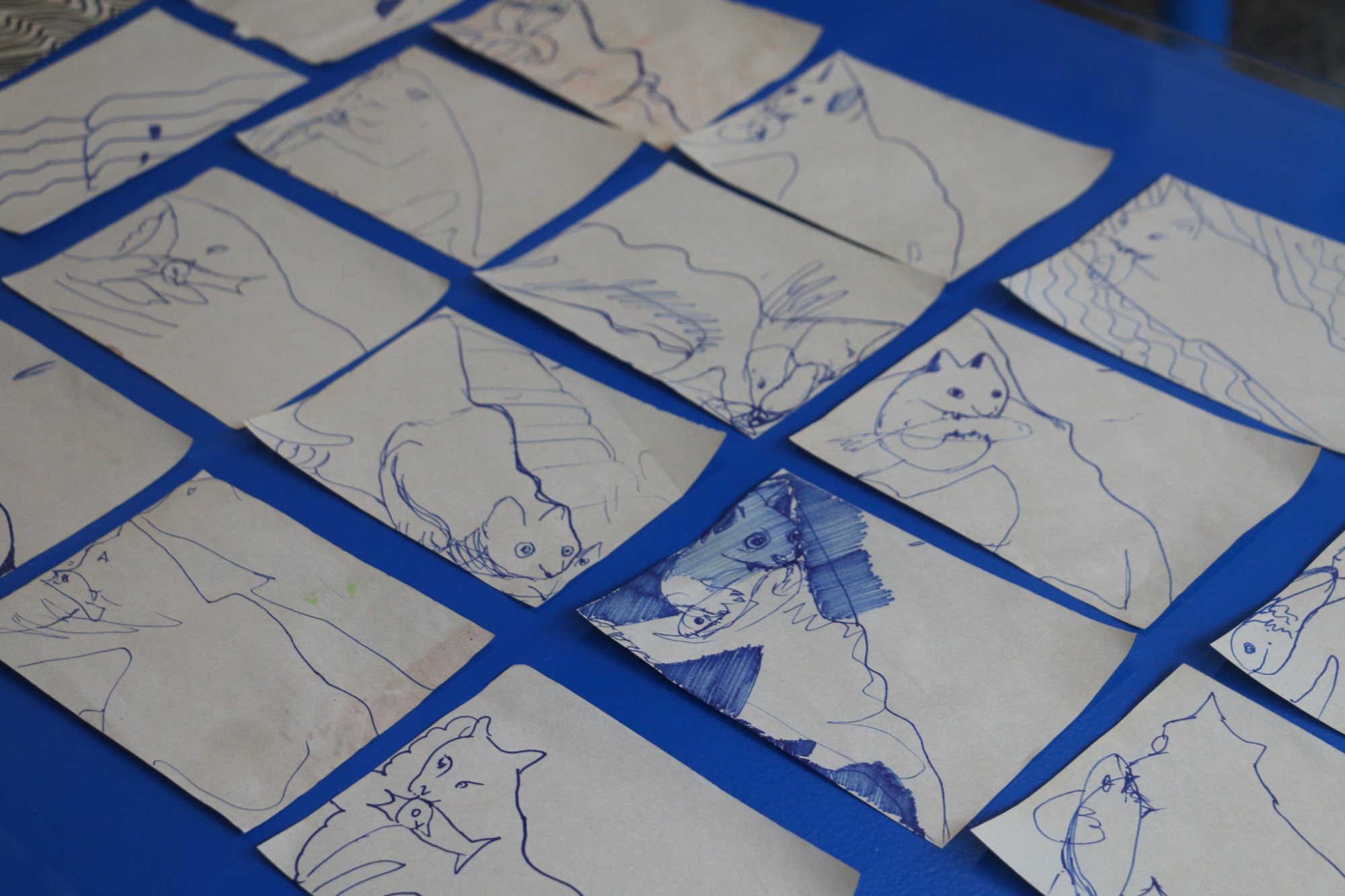 A close up image of a blue table with many line drawings, all made with the same pen and with variations of similar compositions.