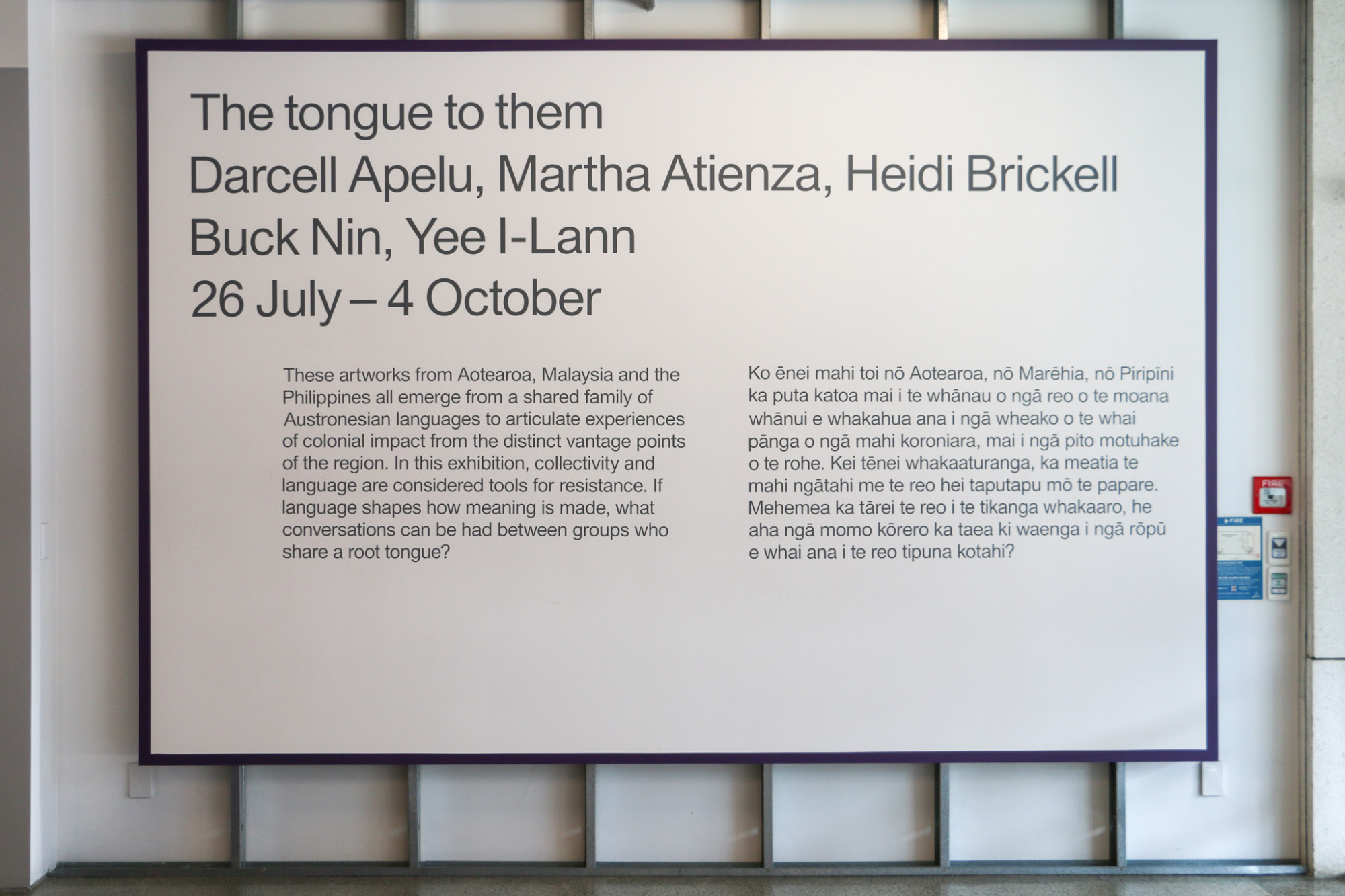 Image of exhibition wall text on a large board with a grey text and purple border hung on the gallery wall.
