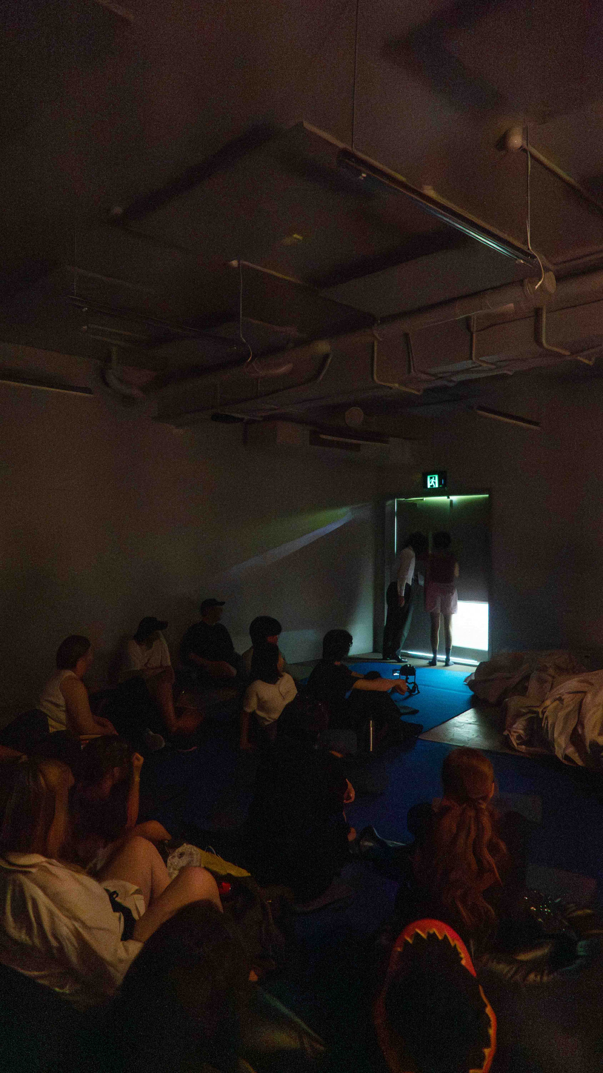 Two person opening the door of a very dark room, leaking light into the space